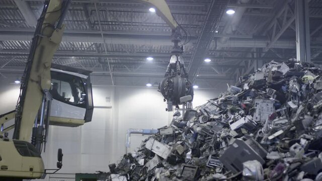 Excavator claw grabs trash on a heap in a landfill