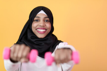 afro muslim woman promotes a healthy life, holding dumbbells in her hands
