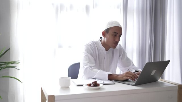 happy asian muslim man meeting using laptop for video call conference