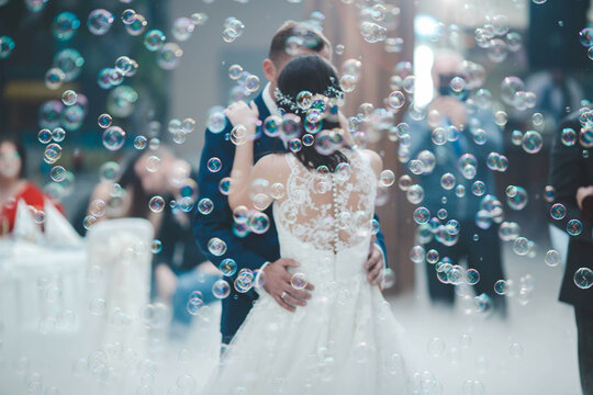 Newly married couple dancing during the wedding celebration surrounded by soap bubbles