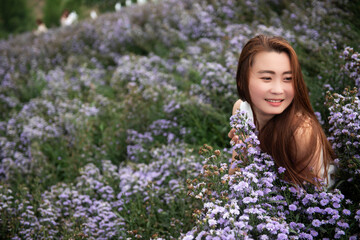 young attractive beautiful happy asian woman with white dress and soft touch purple aster margaret flower field, Travel lifestyle concept in winter.Travel and Lifestyle Concept.