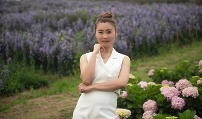 young attractive beautiful happy asian woman with white dress and soft touch purple aster margaret flower field, Travel lifestyle concept in winter.Travel and Lifestyle Concept.