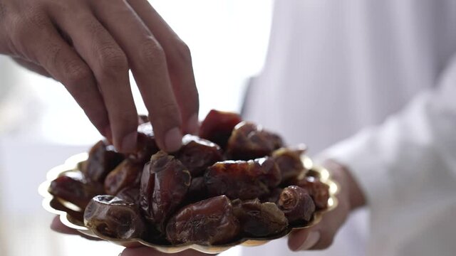 close up of muslim's hand taking dates fruit while enjoying iftar dinner together during a ramadan feast at home