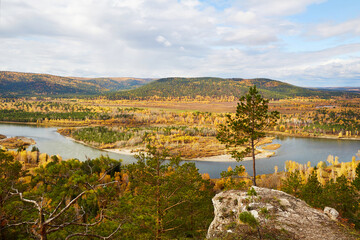 Obraz premium Beautiful view from the cliff to the river, forest. Autumn landscape, cloudy sky. 