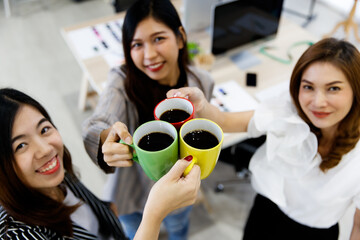 Three colorful coffee mugs held and cheers by Asian young happy successful female stylish fashion...