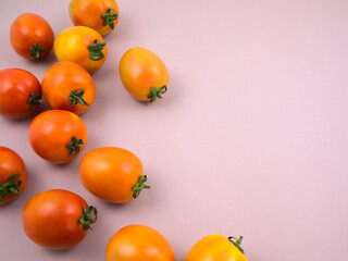 Yellow and red fresh ripe tomatoes flat lay on gray background. Tilted top view, horizontal, still life, off-center, deep depth of field with free space for design image style.