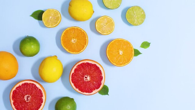 Sliced citrus grapefruit, lemons, orange and limes appear on bright blue background. Stop motion flat lay
