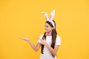 adorable kid presenting product. paschal spring holiday. copy space. happy teen girl wear bunny ears