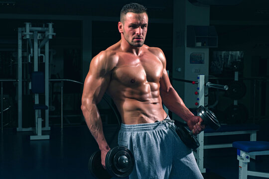 Fitness muscular body. Gym training. Man bodybuilder doing exercises with dumbbell.