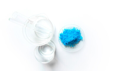 Copper(II) sulfate in Chemical Watch Glass, test tube, Stirring Rod and alcohol in beaker place on white laboratory table. Top view