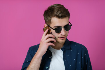 a young man wearing a blue shirt and sunglasses using a smartphone