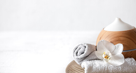 Spa composition with aroma diffuser, towel and orchid flower as decor.