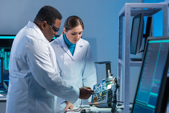 Diverse team of microelectronic engineers discuss current developments in a science lab. Workplace of microprocessor designers. The concept of innovations and inventions of the future.