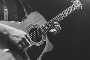 Guitarist playing acoustic guitar in the dark.