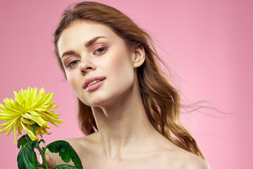 Beautiful woman naked shoulders yellow flower charm cosmetics pink background