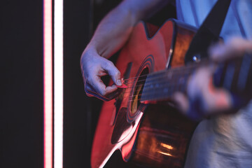 Close up of a guitarist playing an acoustic guitar in a dark room.