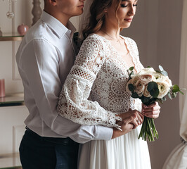 Portrait of the bride and groom in a lace dress in boho style with a bouquet.