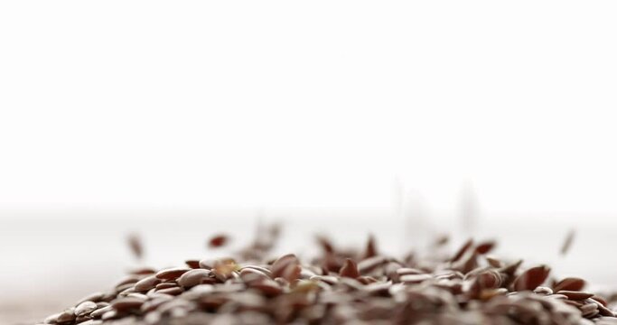 Closeup flax seed falling, isolated on white background. Slow motion. Food background. 