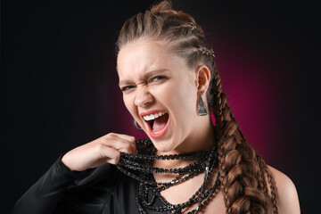 Aggressive young woman with braided hair on dark background
