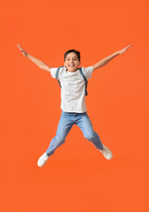 Fototapeta na wymiar Jumping little schoolboy on color background
