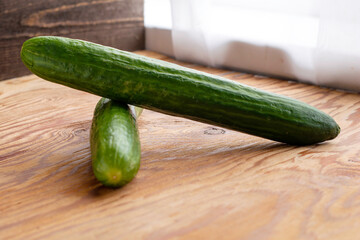 two green cucumbers on the wooden surface of the table