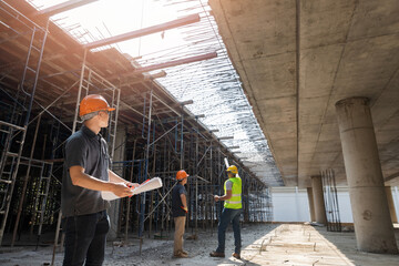 Architect, Engineer, Contractor, or Construction manager holding digital tablet standing with a group of worker at a construction site.