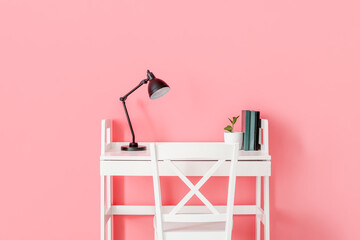 Modern workplace with lamp on color background
