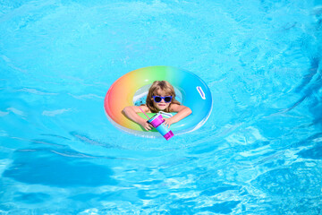Kid in swimming pool, relax swim on inflatable ring and has fun in water on summer vacation, blue water background, copy space. Panorama blue sea wave.