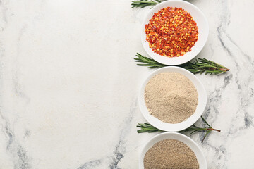 Bowls with different spices and rosemary on light background