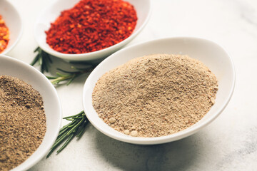 Bowls with different spices and rosemary on light background, closeup