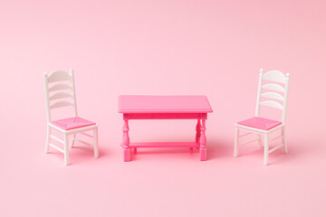 Obraz premium Red table with two chairs on a pink background.