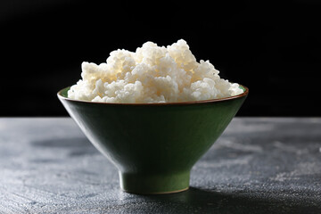 Bowl with tasty rice on dark background