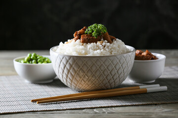 Bowls with tasty rice and meat on dark background