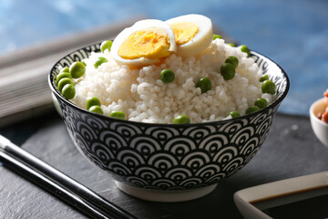 Bowl with tasty rice, green peas and egg on color background