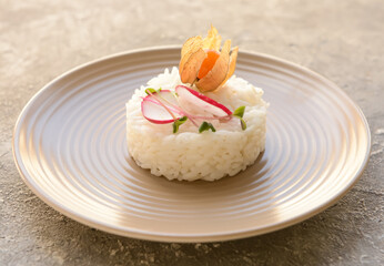 Plate with tasty rice and physalis on grey background