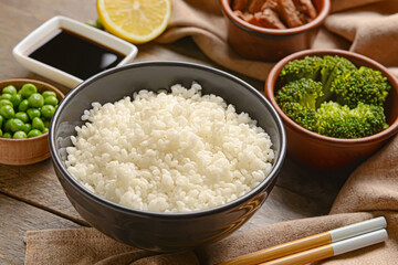 Bowl with tasty rice on wooden background, closeup