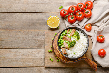 Bowl with tasty rice, meat and vegetables on wooden background