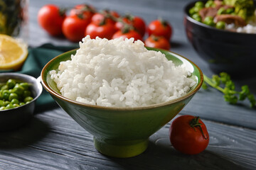 Bowl with tasty rice and vegetables on dark wooden background