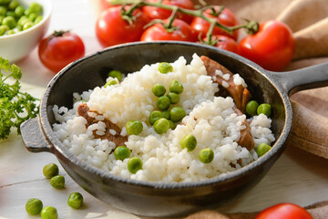 Frying pan with tasty rice, meat and green peas, closeup