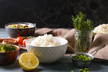 Composition with bowl of tasty rice on dark background