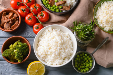 Bowls with tasty rice and vegetables on dark wooden background