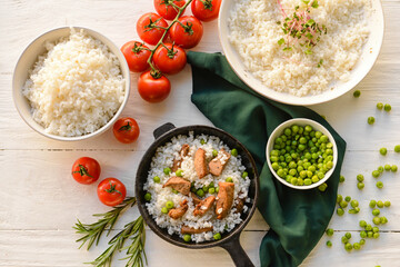 Frying pan with tasty rice, meat and green peas on light wooden background