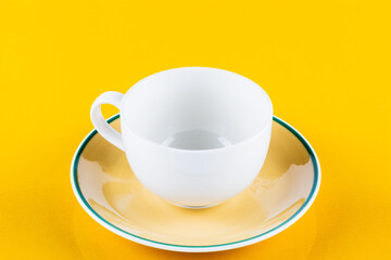 Empty white coffee cup on yellow background.