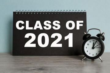 A word CLASS OF 2021 on black notebook with clock. Concept for time management and business.