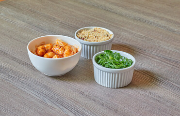 3 white bowls with cabbage, crumbs, and gnocchi on a textured wooden table.