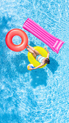 Active young girl in swimming pool aerial top view from above, child relaxes and swims on inflatable ring donut and has fun in water on family vacation, tropical holiday resort
