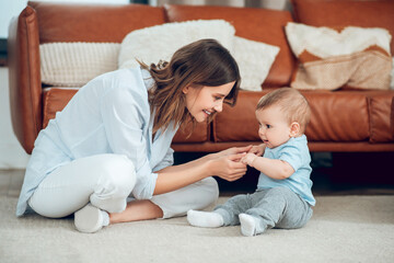 Mom and baby sitting on floor opposite each other