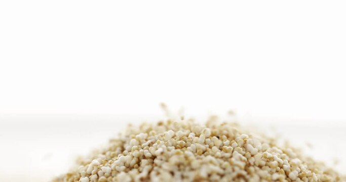 Closeup amaranth groats falling, isolated on white background. Slow motion. Food background. 