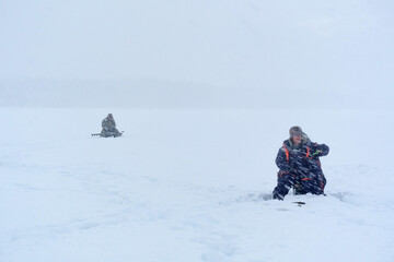 Fototapeta na wymiar fishermen catch fish in winter in heavy snowfall. soft focus