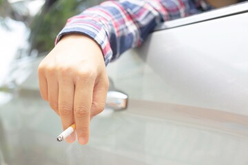 Woman driving a car smokes, focus on cigarettes